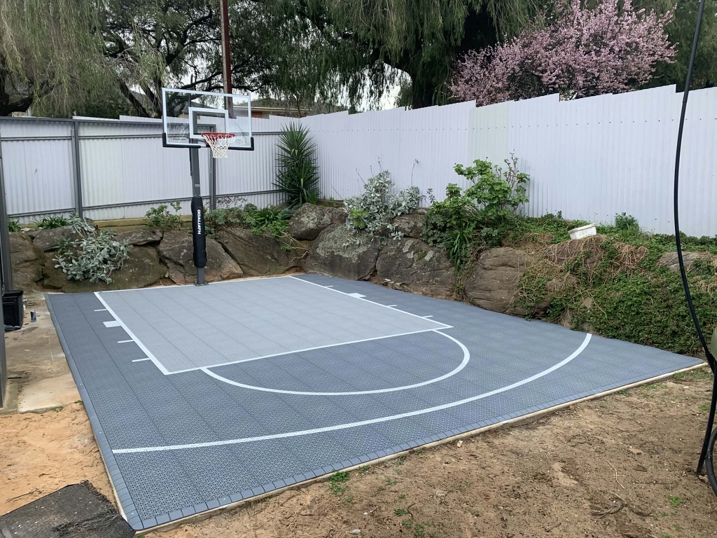 Grey tiled half court framed by a natural rock retaining wall