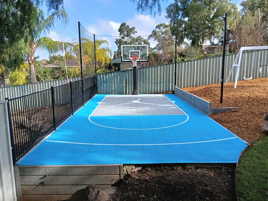 Sky blue and grey court with fencing, netting and pole lighting