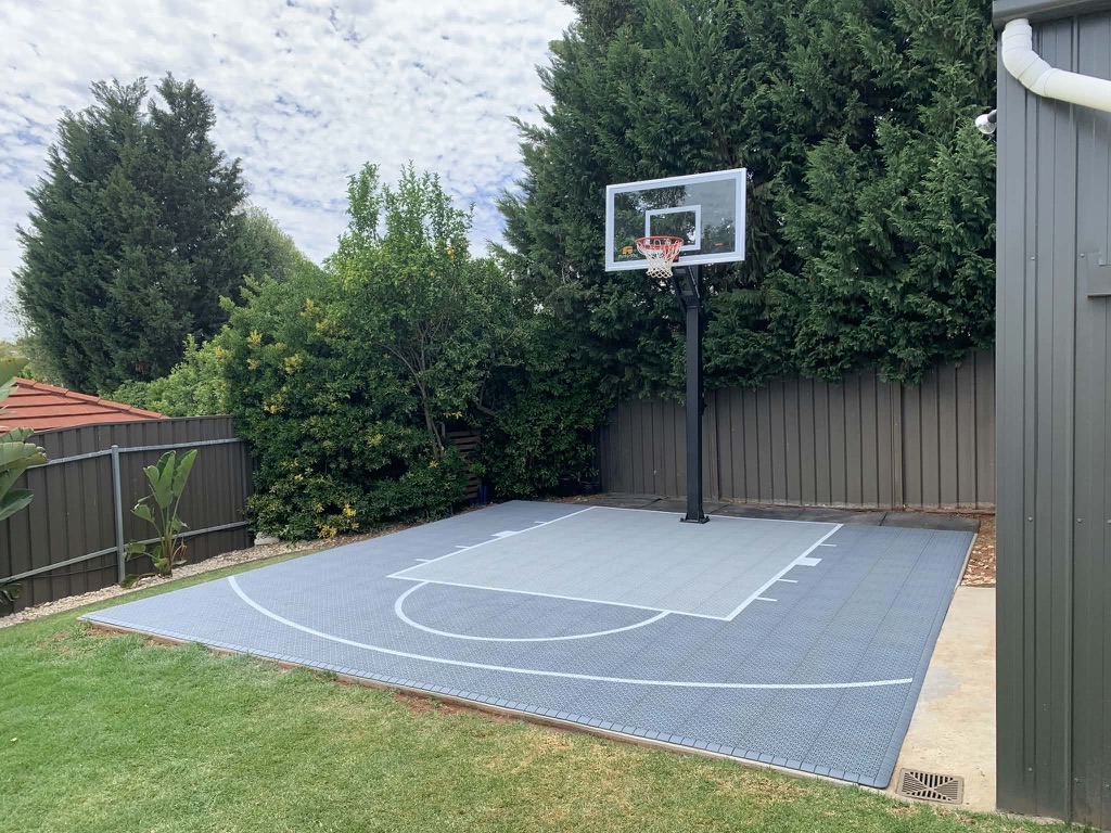 Grey tiled backyard court beside a shed with lawn surrounds