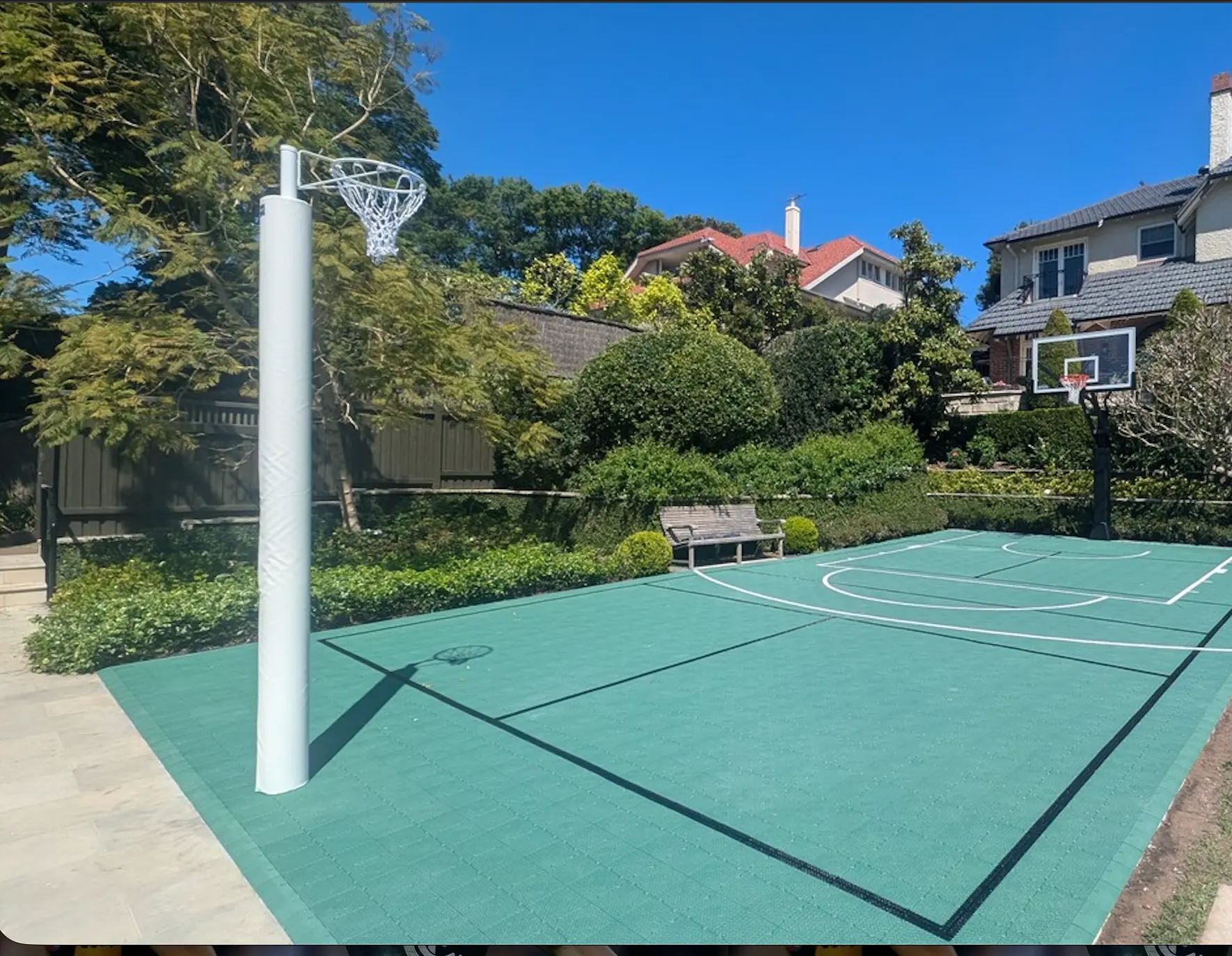 Green multi-sport court with netball ring and basketball hoop