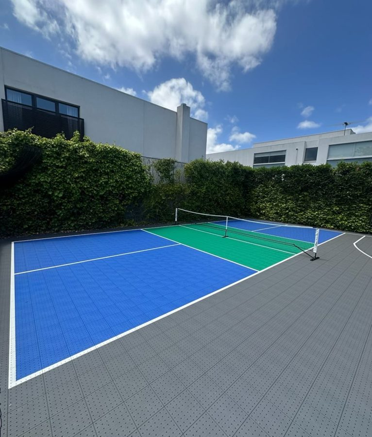 Blue and green tiled pickleball and tennis court with net in place