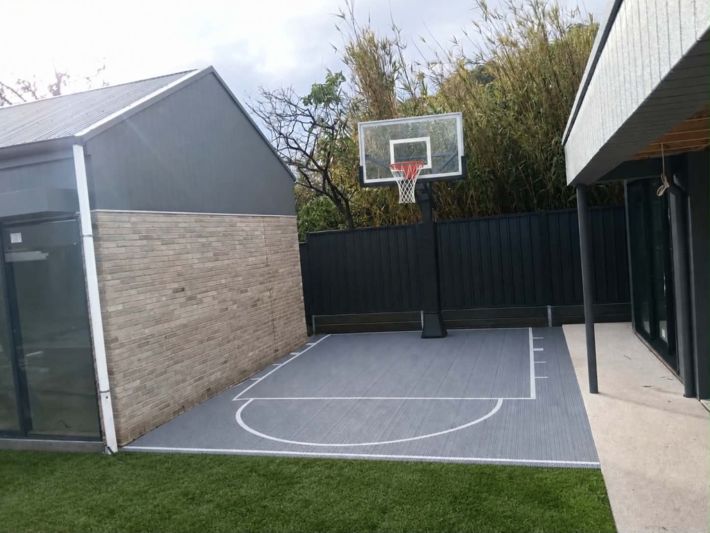 Grey modular tile court installed beside a home