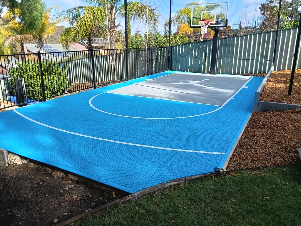 Sky blue and grey court with black fencing and containment netting
